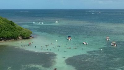 Baigneurs et bateaux sur un banc de sable aux eaux turquoise